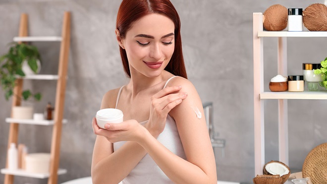 chica aplicándose crema corporal